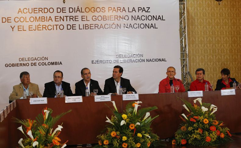 El equipo de negociación del gobierno de Colombia, a la izquierda, y la delegación del Ejército de Liberación Nacional, sentados a la mesa en la firma de un acuerdo para iniciar conversaciones de paz, en Caracas, Venezuela, el 30 de marzo de 2016. (AP Foto/Ariana Cubillos, Archivo)