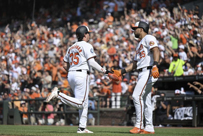Adley Rutschman (35), de los Orioles de Baltimore, celebra con Anthony Santander (25) después de anotar una carrera con un sencillo de Ryan Mountcastle contra el lanzador de los Padres de San Diego, Adrian Morjón, durante la octava entrada el domingo 28 de julio de 2024, en Baltimore. (AP Foto/Terrance Williams)