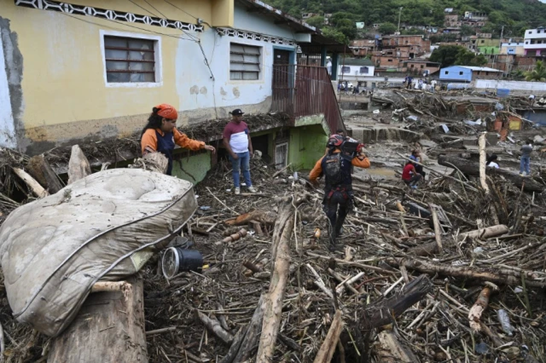 Los residentes ayudan a los rescatistas a desenterrar el lodo de las casas destruidas mientras buscan víctimas o sobrevivientes de un deslizamiento de tierra durante las fuertes lluvias en Las Tejerias, estado de Aragua, Venezuela, el 9 de octubre de 2