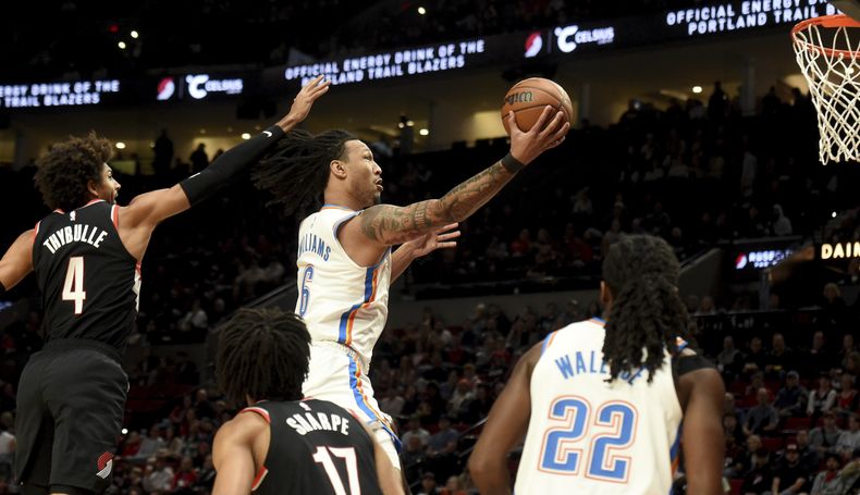 Jaylin Williams, derecha, del Thunder de Oklahoma City, se enfila a la canasta en contra de los Trail Blazers de Portland, dejando atrás a Matisse Thybulle, izquierda, durante la primera mitad del juego de baloncesto de la NBA, el domingo 19 de noviembre de 2023, en Portland, Oregon. (AP Foto/Steve Dykes)
