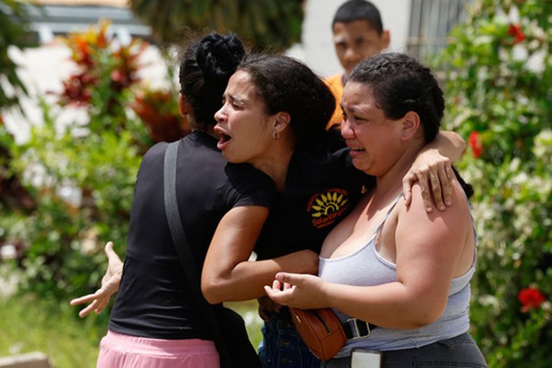 Personas consuelan a Gabriela Rojas, en el centro, mientras llora frente a su casa dañada, donde dos de sus hijos fallecieron durante los terremotos que sacudieron La Guaira, Venezuela, el jueves 25 de junio de 2026. (AP Foto/Pedro Mattey)
