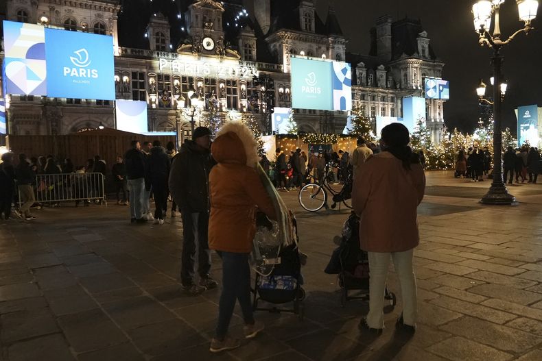 Migrantes esperan en la plaza del Ayuntamiento de París, el lunes 25 de diciembre de 2023, mientras buscan algún sitio para alojarse. (AP Foto/Nicolas Garriga)