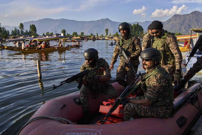 Soldados paramilitares patrullan desde una embarcación mientras turistas indios pasean en barca por el lago Dal, en Srinagar, en la Cachemira controlada por India, el 25 de abril de 2025. (AP Foto/Dar Yasin)