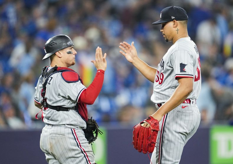 El dominicano Jhoan Durán, relevista de los Mellizos de Minnesota, festeja con el puertorriqueño Christian Vázquez, tras el duelo ante los Azulejos de Toronto, el viernes 9 de junio de 2023 (Mark Blinch/The Canadian Press via AP
