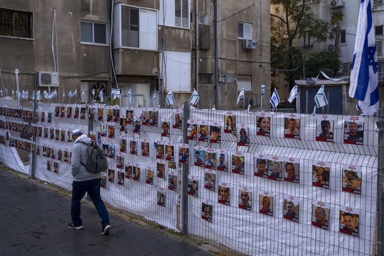 Un hombre pasa junto a una cerca con fotografías de los rehenes, en su mayoría civiles, que fueron capturados por insurgentes de Hamás durante su incursión en el sur de Israel el pasado 7 de octubre, en Ramat Gan, Israel, el 22 de noviembre de 2023. (AP Foto/Oded Balilty)