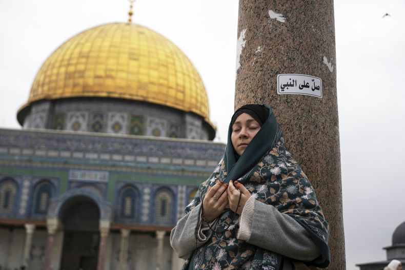 Una mujer ora en el complejo de la mezquita de Al-Aqsa en el primer viernes de ramadán en la Ciudad Vieja de Jerusalén, el viernes 7 de marzo de 2025. El letrero en árabe arriba a la derecha dice: Orar por el Profeta (AP Foto/Mahmoud Illean)