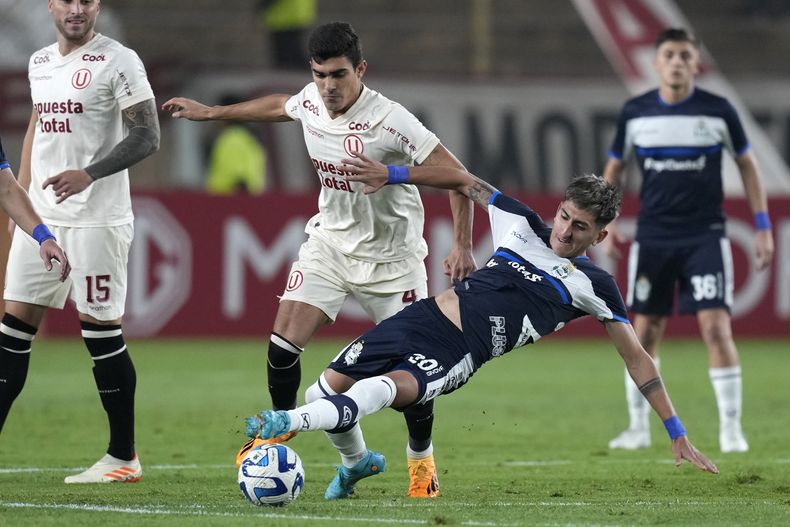 Alfonso Barco, de Universitario de Perú, conduce el balón ante la barrida de Alan Lescano, de Gimnasia y Esgrima de Argentina, en un partido de la Copa Sudamericana, disputado el jueves 28 de junio de 2023 (AP Foto/Martín Mejía)