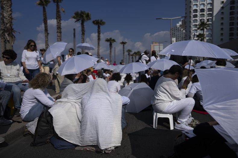 Un grupo de activistas ocupan una calle con sombrillas en una protesta para exigir la liberación de los rehenes en la Franja de Gaza, frente a la oficina de la embajada estadounidense en Tel Aviv, Israel, el viernes 31 de enero de 2025. (AP Foto/Oded Balilty)