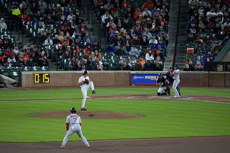 En foto del 24 de abril del 2023, el reloj de lanzamiento es visible antes de que el abridor de los Orioles Baltimore Dean Kremer lance. Enrique Hernández de los Medias Rojas está al bat y Masataka Yoshida está en segunda base en la sexta entrada. (AP Foto/Julio Cortez)