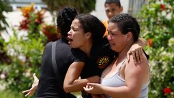 Personas consuelan a Gabriela Rojas, en el centro, mientras llora frente a su casa dañada, donde dos de sus hijos fallecieron durante los terremotos que sacudieron La Guaira, Venezuela, el jueves 25 de junio de 2026. (AP Foto/Pedro Mattey)