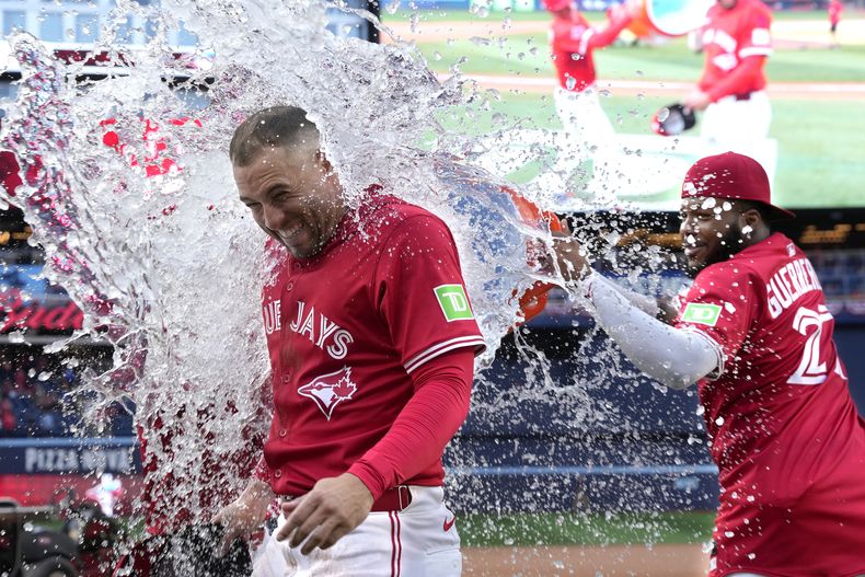 El dominicano Vladimir Guerrero, de los Azulejos de Toronto, lanza agua helada a su compañero George Springer tras la victoria sobre los Yankees de Nueva York, el martes 1 de julio de 2025 (Frank Gunn/The Canadian Press via AP)