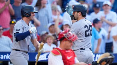 Austin Wells (derecha), de los Yankees de Nueva York, celebra su cuadrangular con Ryan McMahon (izquierda), mientras el receptor de los Filis de Filadelfia, J.T. Realmuto (centro), revisa su equipo durante la tercera entrada de un partido de béisbol, el sábado 25 de julio de 2026, en Filadelfia. (Foto AP/Chris Szagola)