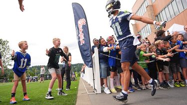El receptor abierto de los Seahawks de Seattle, Jaxon Smith-Njigba, saluda a jóvenes aficionados mientras sale al campo durante el campamento de entrenamiento del equipo de la NFL, el domingo 26 de julio de 2026, en Renton, Washington. (Foto AP/Lindsey Wasson)