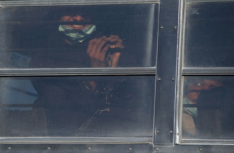 Un migrante esposado sonríe mientras es trasladado en autobús para abordar un vuelo de repatriación del Servicio de Control de Inmigración y Aduanas de Estados Unidos (ICE, por sus siglas en inglés) hacia Guatemala, el miércoles 10 de mayo de 2023, en El Paso, Texas. A partir del jueves, el gobierno del presidente Joe Biden comenzará a negar asilo a los migrantes que se presenten en la frontera con México sin haber presentado primero una solicitud en línea o pedido protección en un país por el que pasaron, según una nueva regla dada a conocer el miércoles. Las autoridades federales han advertido sobre complicaciones en los próximos días una vez que expire la medida conocida como Título 42, la cual permitía deportar rápidamente a los migrantes para prevenir la propagación del COVID-19. (AP Foto/Andrés Leighton)