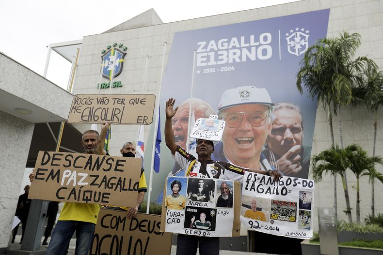 Aficionados del exjugador y seleccionador de Brasil Mario Zagallo sostienen pancartas afuera de las instalaciones de la Confederación de Brasil en donde se realiza el fúneral de Zagallo el domingo 7 de enero del 2024. (AP Foto/Bruna Prado)