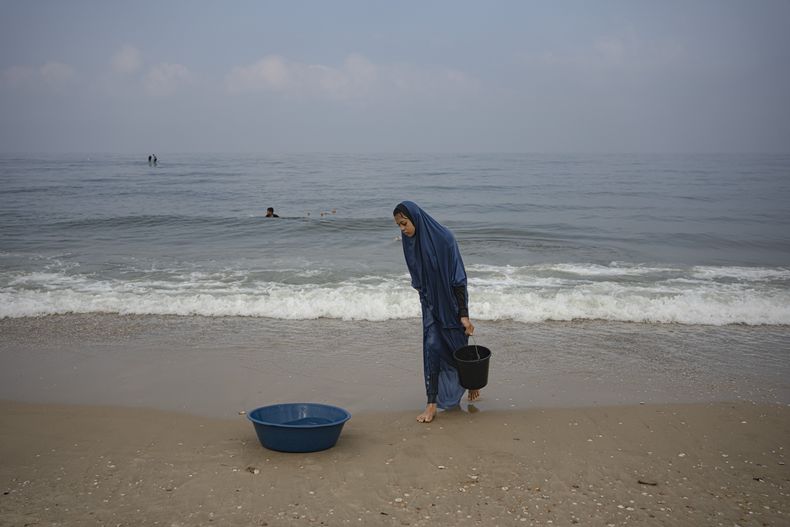 Una mujer palestina recoge agua del mar para lavar la ropa en la playa de Deir al Balah, en la Franja de Gaza, el 2 de noviembre de 2023. (AP Foto/Fatima Shbair)