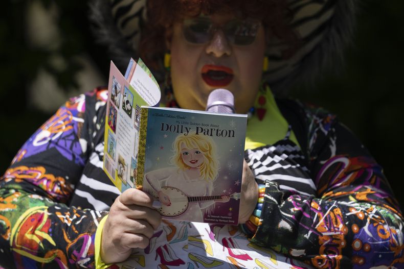 La drag queen Alexus Daniels lee My Little Golden Book About Dolly Parton a niños durante la actividad Drag Storytime! en Mt. Carmel, Pensilvania, en el jardín en Pink Moon Collective, el sábado 6 de mayo de 2023. (Foto AP/Carolyn Kaster)