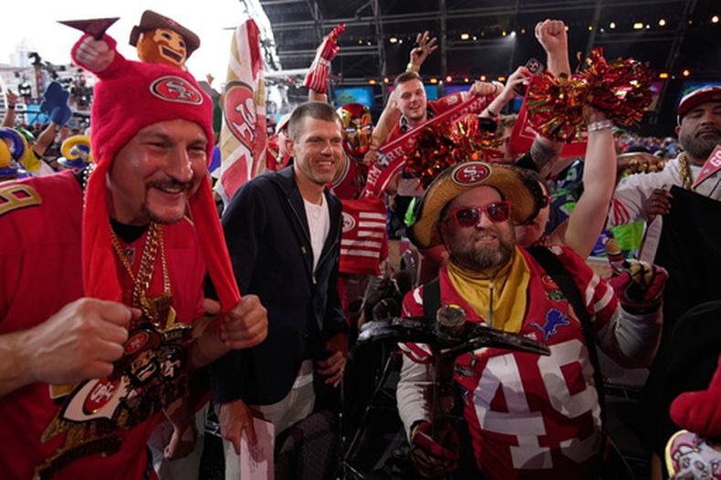 Andy Lee (centro), ex jugador de la NFL, posa con aficionados de los 49ers de San Francisco durante la segunda ronda del draft de la liga, el viernes 24 de abril de 2026, en Pittsburgh. (AP Foto/Sue Ogrocki)