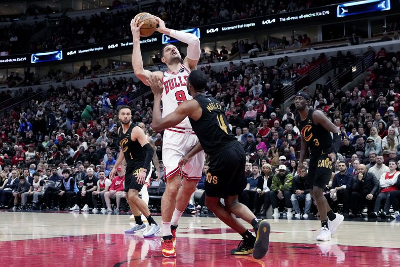El centro de los Bulls de Chicago Nikola Vucevic (9) conduce hacia el aro ante el alero de los Cavaliers de Cleveland Evan Bombley durante el primer tiempo extra del juego de baloncesto de la NBA, en Chicago, el miércoles 28 de febrero de 2024. (AP Foto/Nam Y. Huh)