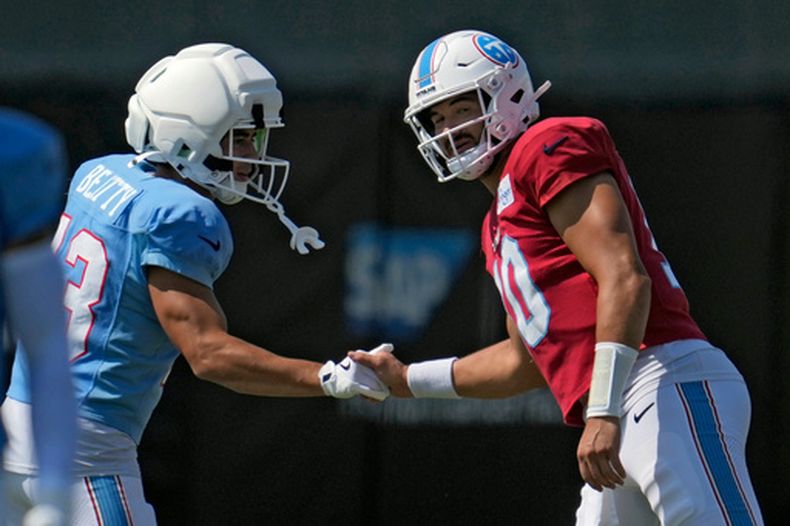 Mitchell Trubisky (10), quarterback de los Titans de Tennessee, estrecha la mano con Hank Beatty (13), receptor, durante una práctica conjunta de su equipo con los 49ers de San Francisco, el martes 11 de agosto de 2026, en Santa Clara, California. (AP Foto/Jeff Chiu)