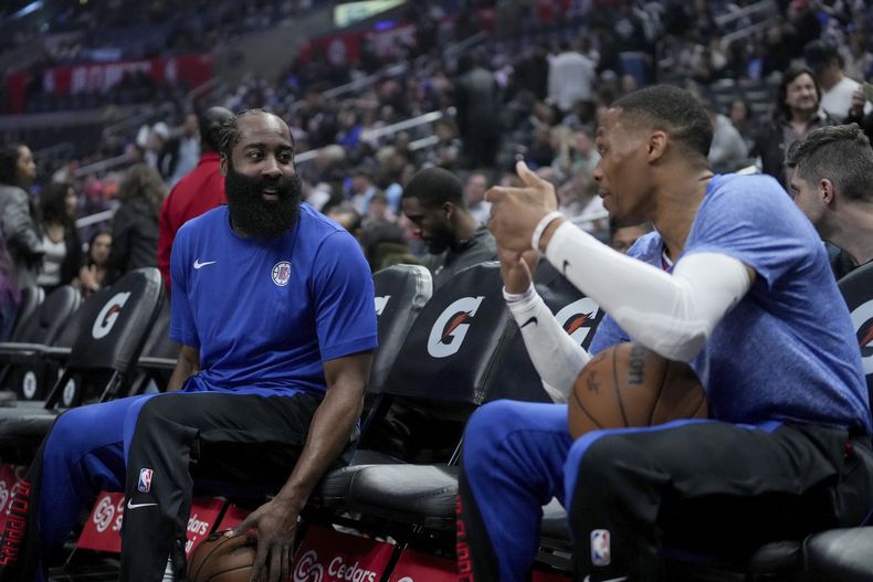 El armador de los Clippers de Los Ángeles James Harden (izquierda), y el base Russell Westbrook platican en el banquillo previo al juego de baloncesto de la NBA ante el Jazz de Utah, en Los Ángeles, el viernes 12 de abril de 2024. (AP Foto/Eric Thayer)