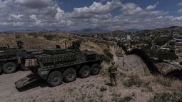 El sargento del Ejército estadounidense Salvador Hernández, parado junto a vehículos de combate Stryker, observa la cerca fronteriza entre Estados Unidos y México desde una colina, el 22 de julio de 2025, en Nogales, Arizona. (AP Foto/Jae C. Hong)
