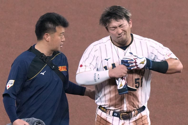 Seiya Suzuki es ayudado a salir del campo tras lesionarse en la segunda base durante la primera entrada de un juego de cuartos de final del Clásico Mundial de Béisbol contra Venezuela, el sábado 14 de marzo de 2026, en Miami. (Foto AP/Marta Lavandier)