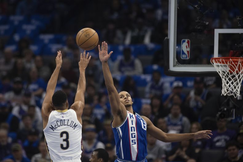 CJ McCollum (3), de los Pelicans de Nueva Orleans, dispara sobre Keegan Murray, derecha, de los Kings de Sacramento, en el primer cuarto del juego de baloncesto de la NBA, en Sacramento, el lunes 4 de diciembre de 2023. (AP Foto/José Luis Villegas)