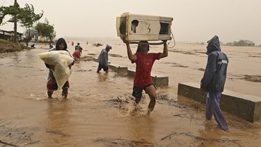Dos personas cargan sus pertenencias junto a un río crecido tras intensas lluvias causadas por el tifón Toraji, el lunes 11 de noviembre de 2024, en Ciudad Ilagan, provincia de Isabela, en el norte de Filipinas. (AP Foto/Noel Celis)