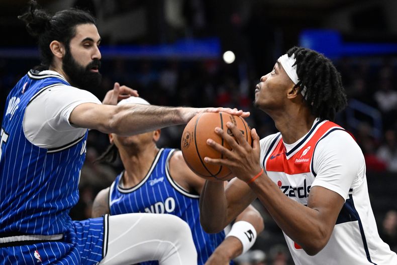 Goga Bitadze, pívot del Magic de Orlando, a la izquierda, bloquea el tiro de Bilal Coulibaly, guardia de los Wizards de Washington, durante la primera mitad de un juego de baloncesto de la NBA, el sábado 1 de noviembre de 2025, en Washington. (AP Photo/John McDonnell)
