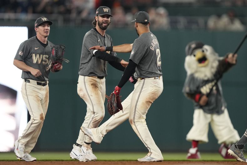 El jardinero de los Nacionales de Washington, Jesse Winker, centro, y el segunda base de los Nacionales de Washington, Luis García Jr., (2), a la derecha, se dan la mano al final de su juego de béisbol contra los Orioles de Baltimore en el Nationals Park en Washington, el martes 7 de mayo de 2024. Los Nacionales vencieron 3-0 a los Orioles. El jardinero de los Nacionales de Washington, Jacob Young, está a la izquierda. (AP Foto/Susan Walsh)