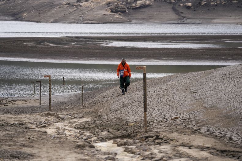 Un trabajador de la empresa de agua de Bogotá monitorea el nivel del embalse de San Rafael, una fuente de agua potable para Bogotá que está bajo debido al fenómeno climático de El Niño, en La Calera, en las afueras de Bogotá, Colombia, el lunes 8 de abril de 2024. (AP Foto/Iván Valencia)