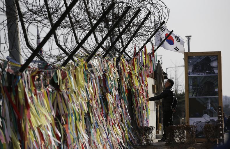 Un hombre lee un mensaje en un list&oacute;n en una cerca y en el que se desea la reunificaci&oacute;n de ambas coreas en el pabell&oacute;n de Imnjigak, cerca de la aldea fronteriza de Panmunjom, en Paju, al norte de Se&uacute;l, Corea del sur, el vierne