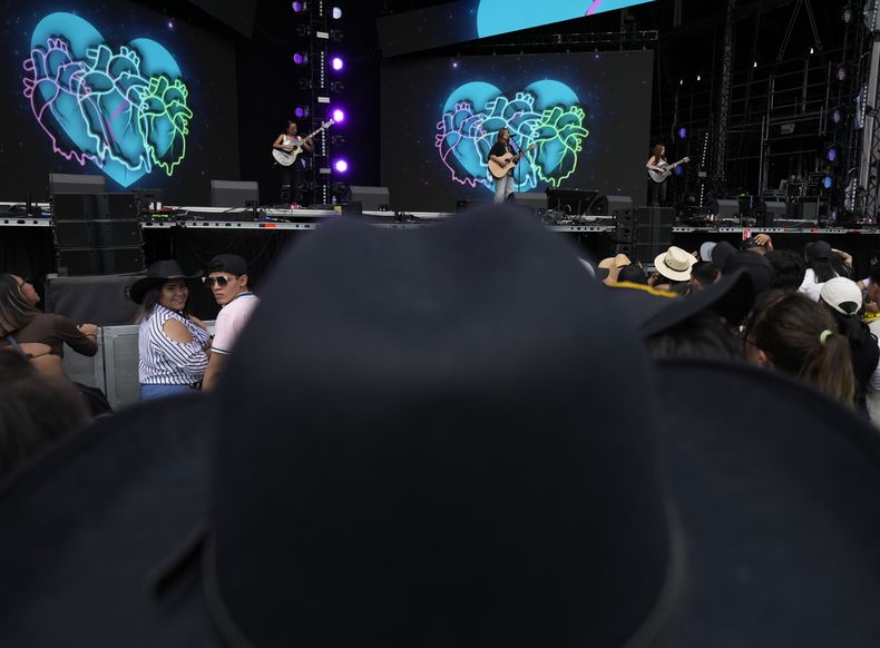 Un fan con sombrero mira al trío estadounidense Conexión Divina durante su concierto en el primer día del festival Arre en la Ciudad de México el sábado 10 de septiembre de 2023. (Foto AP/Fernando Llano)