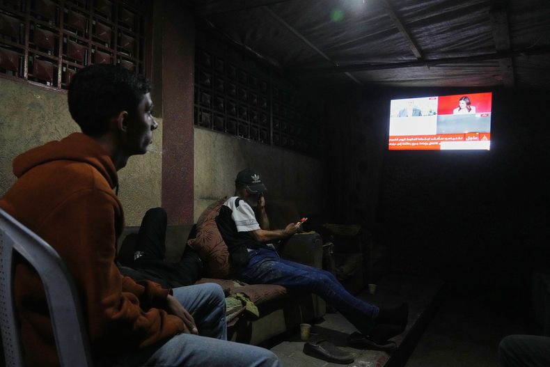 Palestinos ven las noticias en un televisor tras el anuncio de que Israel y Hamás han acordado la primera fase de un plan de paz, mientras se sientan en una tienda de campaña frente al hospital Al-Aqsa, en Deir al-Balah, en el centro de la Franja de Gaza, el jueves 9 de octubre de 2025. (AP Foto/Abdel Kareem Hana)