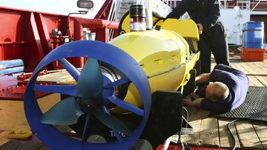 americateve | Foto del 17 de abril del 2014 de la Fuerza de Defensa Australiana de los empleados Evan Tanner, fondo a la derecha, y Chris Minor, de Phoenix International, inspeccionando el submarino Artemis en la cubierta del buque australiano Ocean Shield, para buscar