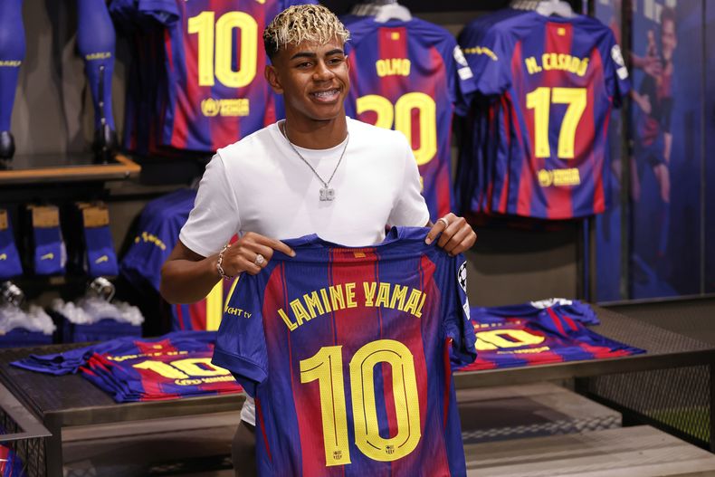 Lamine Yamal posa con su nueva camiseta del Barcelona tras firmar una extensión de contrato, el miércoles 16 de julio de 2025. (AP Foto/Joan Monfort)