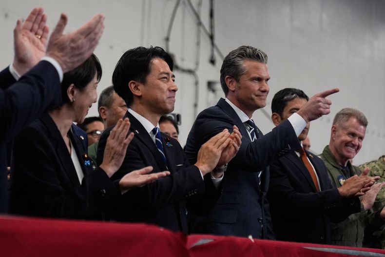 El secretario de Defensa de EEUU, Pete Hegseth, en el centro a la derecha, con la primera ministra japonesa, Sanae Takaichi, a la izquierda, y el ministro de Defensa, Shinjiro Koizumi, mientras escuchan al presidente Donald Trump hablar con miembros del Ejército a bordo del USS George Washington, un portaaviones atracado en una base naval estadounidense, en Yokosuka, al sur de Tokio, el martes 28 de octubre de 2025. (AP Foto/Mark Schiefelbein)