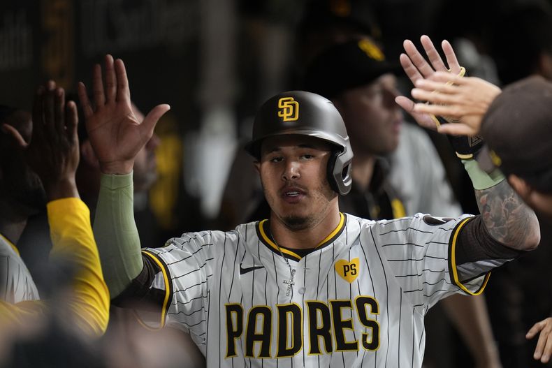 El dominicano Manny Machado, de los Padres de San Diego, recibe felicitaciones en la cueva luego de anotar en el juego ante los Rojos de Cincinnati, el martes 30 de abril de 2024 (AP Foto/Gregory Bull)