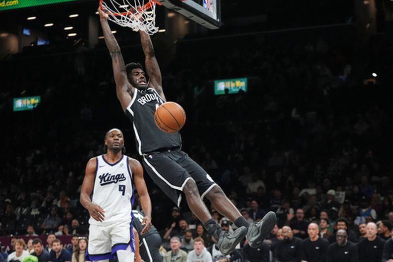 Drake Powell (4), de los Nets de Brooklyn, realiza una volcada frente a Precious Achiuwa (9), de los Kings de Sacramento, durante la segunda mitad de un juego de baloncesto de la NBA, el domingo 29 de marzo de 2026, en Nueva York. (Foto AP/Frank Franklin II)