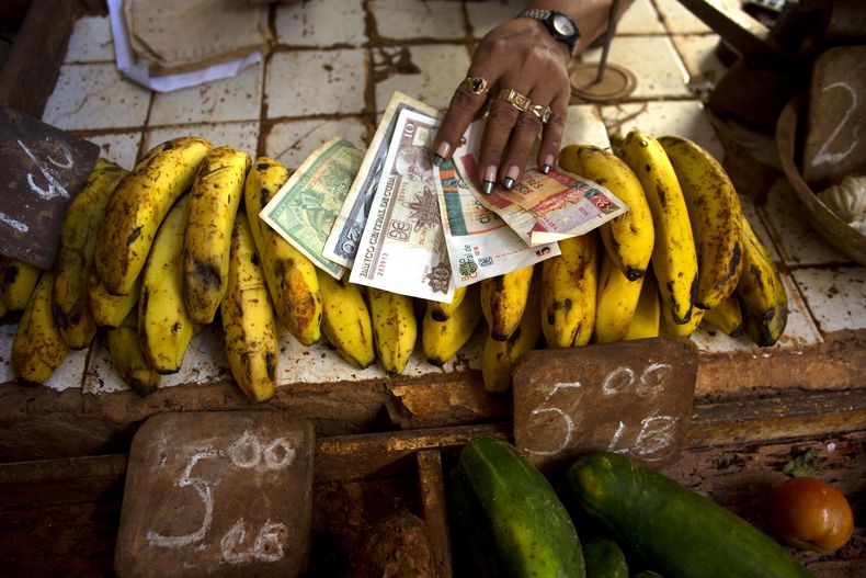 Una vendedora de alimentos muestra pesos convertibles,conocidos como CUC (los dos de la derecha) junto a pesos tradicionales en un mercado de La Habana el 30 de agosto del 2013. El gobierno cubano admite que el sistema de la doble divisa no funciona, pero