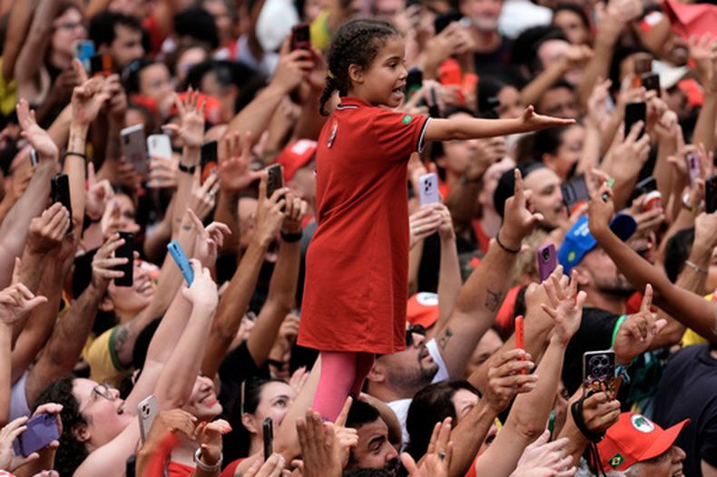 Una niña subida a los hombres de un tío extiende la mano entre una multitud de seguidores del presidente de Brasil, Luiz Inácio da Silva, que busca la reelección, en su último mitin de campaña el día antes de la segunda vuelta electoral en Sao Paulo, Brasil, el sábado 24 de octubre de 2026. (AP Foto/Natacha Pisarenko)