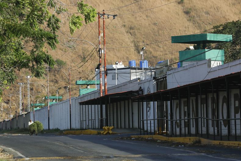 Un hombre en bicicleta pasa frente a la prisión en Tocorón, Venezuela, el sábado 22 de marzo de 2025. (AP Foto/Cristian Hernández)