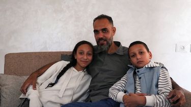 El técnico médico palestino Mohammed Abu Moussa, de 45 años, que fue liberado de detención israelí tras 20 meses, posa para una foto con sus hijos, Jourie y Hamid, en Deir al-Balah, Gaza, el sábado 18 de octubre de 2025. (AP Foto/Abdel Kareem Hana)
