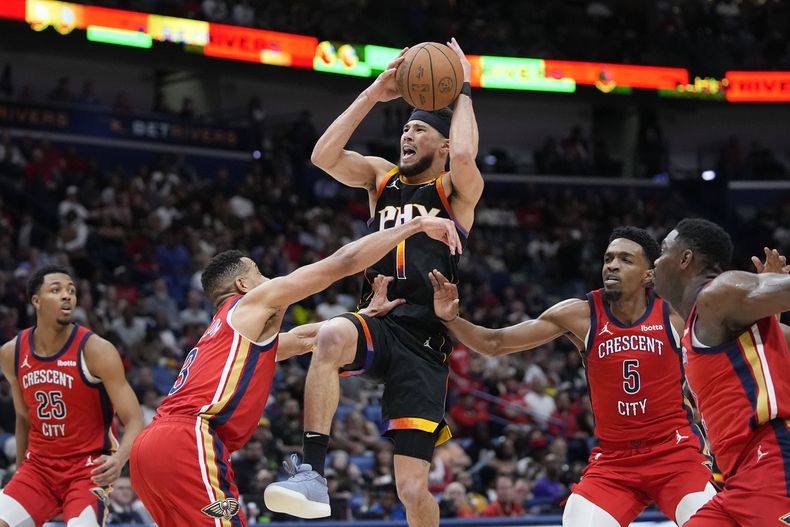 Devin Booker (1), de los Suns de Phoenix, ataca la canasta entre CJ McCollum (3) Herbert Jones (5), de los Pelicans de Nueva Orleans, en el juego de baloncesto de la NBA, el lunes 1 de abril de 2024, en Nueva Orleans. Los Suns ganaron 124-111. (AP Foto/Gerald Herbert)