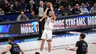 Devin Booker (1), de los Suns de Phoenix, toma un tiro ante la mirada de tres jugadores de los Mavericks de Dallas, Maxi Kleber (42), Tim Hardaway Jr. (10) y Luka Doncic (77) en la segunda mitad del juego de baloncesto de la NBA, en Dallas, el miércoles 24 de enero de 2024. (AP Foto/Tony Gutierrez)