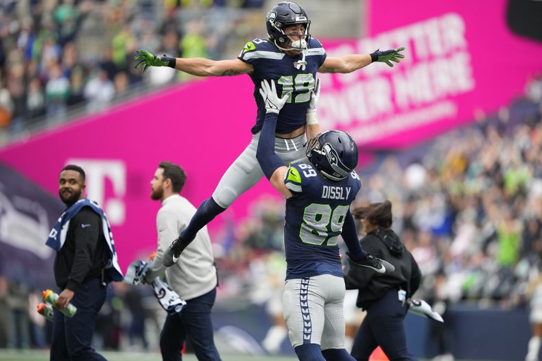 Jake Bobo (19), receptor de los Seahawks de Seattle, celebra su recepción de anotación en contra de los Cardinals de Arizona, con su compañero, el tight end Will Dissly (89) después de que la revisión de la repetición la hiciera válida, durante la primera mitad del juego de la NFL, el domingo 22 de octubre de 2023, en Seattle. (AP Foto/Lindsey Wasson)