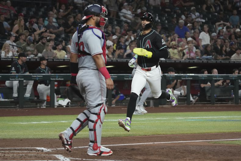 El jugador de los Diamondbacks de Arizona Lourdes Gurriel Jr., a la derecha, corre contra los Nacionales de Washington, en una doble matanza de Kevin Newman en el cuarto inning durante un juego de béisbol, el lunes 29 de julio 2024 en Phoenix, Arizona. (AP FoRick Scuteri)