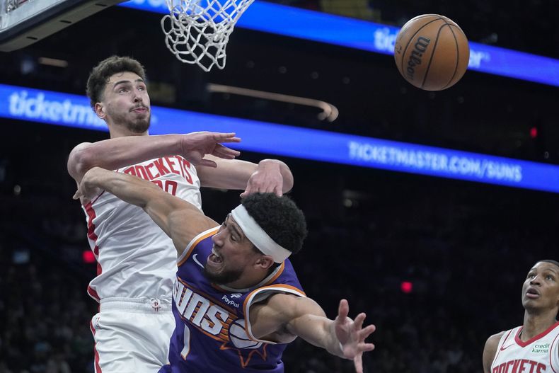 El pívot de los Rockets de Houston, Alperen Sengun (28), bloquea un tiro del escolta de los Suns de Phoenix, Devin Booker (1), durante la segunda mitad del partido de baloncesto de la NBA en Phoenix, el sábado de marzo. 2, 2024. Los Rockets ganaron 118-109. (AP Foto/Darryl Webb)