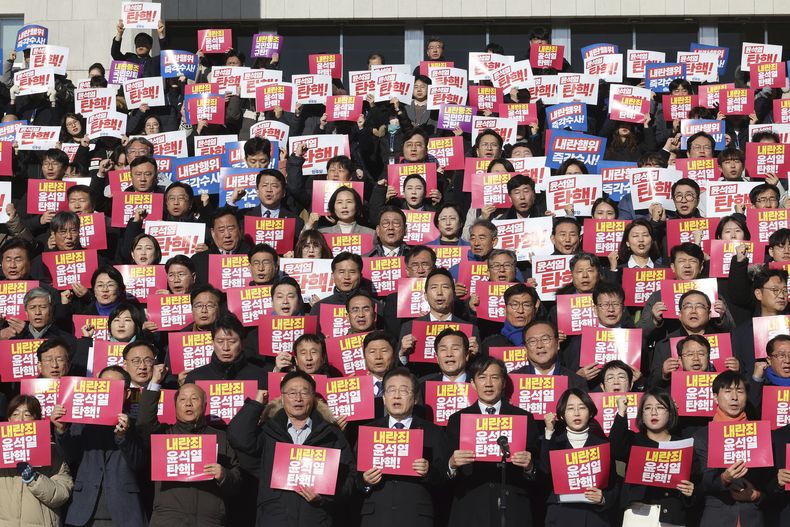 El líder del principal partido de la oposición de Corea del Sur, Lee Jae-myung (abajo, centro), corea consignas durante una conferencia de prensa con miembros de la sociedad civil y de cinco formaciones opositoras más pequeñas contra el gobierno del Partido del Poder Popular, en la Asamblea Nacional en Seúl, Corea del Sur, el 6 de diciembre de 2024. El cartel dice, en coreano ¡Juicio político a Yoon Suk Yeol. (Park Dong-ju/Yonhap vía AP)